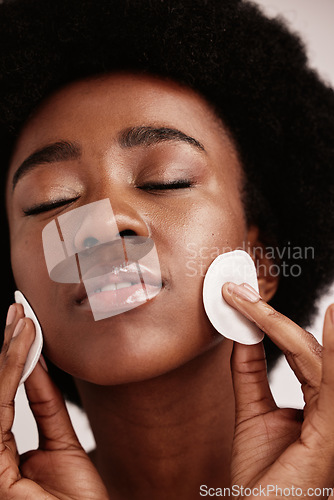 Image of Cleaning face, skin care and cotton for black woman in studio with dermatology, cosmetics and detox. Aesthetic model with hands on natural facial skin to clean makeup, beauty and wellness for spa