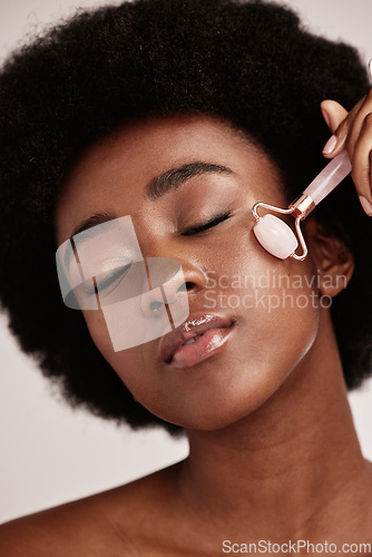 Image of Black woman, skin care and facial roller for face massage in studio with dermatology and cosmetic tools. Aesthetic model with hands for spa product for health, wellness and natural youth skin glow