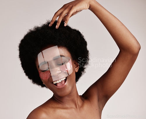 Image of Skincare, beauty and black woman with eye patches for anti ageing treatment isolated on grey background. Health, skin and model with afro, smile and collagen mask on eyes, luxury spa facial in studio