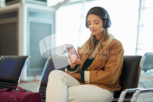 Image of Music headphones, phone and woman at airport lobby on social media, internet browsing or web scrolling. Travel, mobile technology and female with smartphone app for streaming radio, podcast or song.