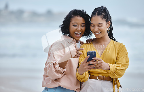 Image of Phone, beach and social media with black woman friends outdoor together by the ocean or sea in the morning. Nature, mobile or internet with a young female and friend reading a text on the coast