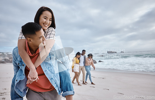 Image of Happy, piggyback or couple of friends at a beach on a relaxing holiday vacation bonding in nature together. Love, man and Asian woman with smile at sea enjoys traveling on ocean trips in Miami, USA