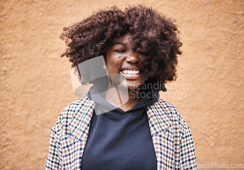 Image of Black woman, smile and happy young person by an orange wall feeling freedom and joy. Happiness, urban fashion and cool laughing African female smiling with afro hair and stylish clothing outdoor