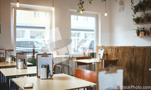 Image of Table, chair and menu in an empty coffee shop in the city ready for service on opening day. Furniture, restaurant and decor on the interior of a small business cafe in the morning waiting to serve
