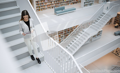 Image of Top view, stairs and woman in library, tablet or online research for university, reading or education. Female, girl or student with device, bookshelves or search internet for knowledge or information