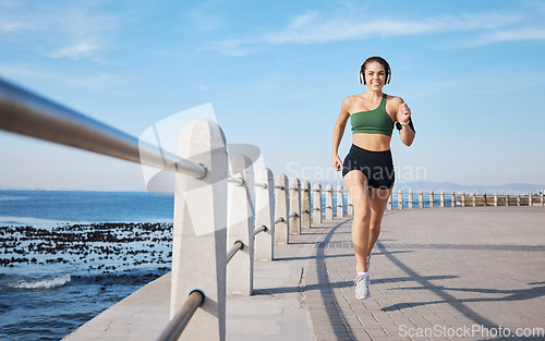 Image of Running, music and woman at beach for fitness, exercise and morning cardio with energy in sports. Radio, podcast and workout run by girl at ocean for training, happy or relax with audio motivation