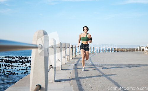 Image of Fitness, woman and running by the beach side in Cape Town for cardio exercise, training or workout. Active female runner enjoying summer run or exercising for healthy wellness in the nature outdoors