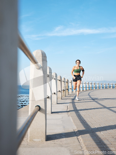 Image of Fitness, woman and running by the beach side for exercise, training or cardio workout in Cape Town. Active female runner enjoying summer run or exercising for healthy wellness in the nature outdoors