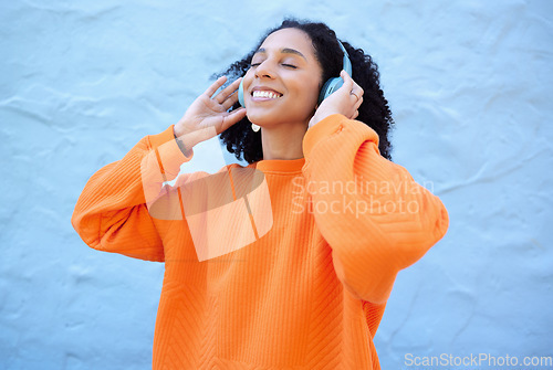 Image of Black woman, headphones and music with smile by wall background on urban adventure, relax and freedom. African gen z girl, streaming audio and quality sound on app, web or internet with peace in city
