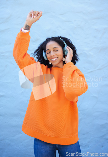 Image of Black woman, headphones and music for dance by wall background on urban adventure, relax or freedom. African gen z girl, streaming audio or quality sound on radio, web or internet for dancing in city