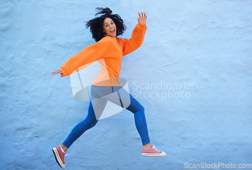 Image of Happy, excited and woman jumping by a wall while walking in the city on a vacation or weekend trip. Happiness, smile and young lady from Mexico with energy, freedom or adventure in town on a holiday.