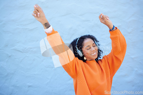 Image of Black woman, hands up or dancing to headphones music on isolated blue background, fashion mockup or wall mock up. Smile, happy or dancer student listening to radio, audio or energy podcast in freedom