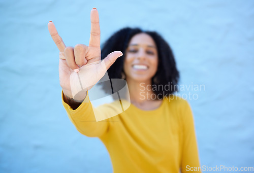 Image of Rock sign, fashion and hands of black woman on blue background with smile, happy mindset and peace. Hand gesture, beauty and face of African girl relax with urban style, trendy and stylish clothes