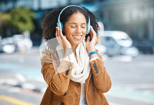 Image of Music, headphones and black woman happy in city for travel, motivation and mindset. Young person on urban street with buildings background listening and streaming podcast or inspiration audio outdoor