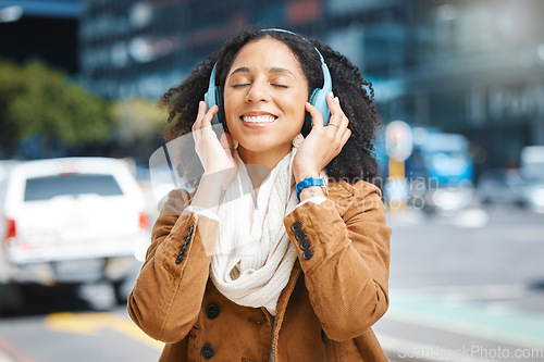 Image of Black woman with headphones for listening to music in city for travel, motivation and happy mindset. Young person on an urban street with buildings background while streaming podcast or audio outdoor