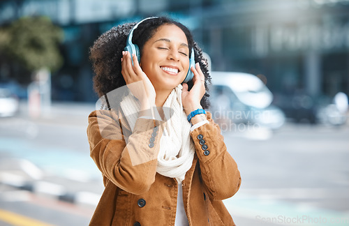 Image of Black woman, music and headphones while happy in city for travel, motivation and mindset. Young person on urban street with radio and sound while listening and streaming podcast or audio outdoor