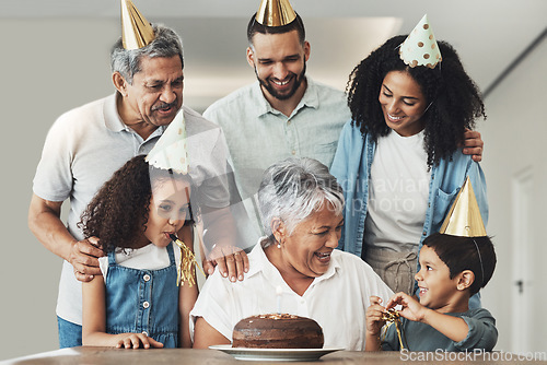 Image of Happy birthday, senior woman and family celebration at a table with a cake, love and care in a house. Children, parents and grandparents together for a party to celebrate excited grandma with dessert