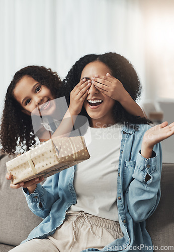 Image of Mother, girl and surprise with gift on sofa in living room for birthday party or event. Family love, wow and portrait of kid surprising happy mama with present box for mothers day on couch in house.