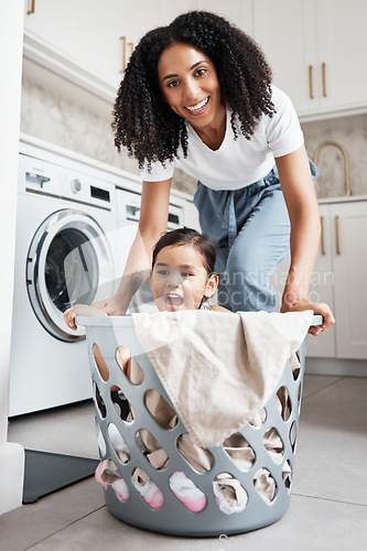 Image of Portrait of a mother with her kid in a laundry basket at their home while washing clothes together. Happiness, housework and face of young woman having fun with girl kid while cleaning the house.