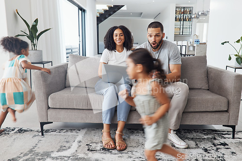 Image of Black family home, children and running in living room for game, bonding or funny time with parents on sofa. Kids, mother and father on lounge couch with laptop, smile and happiness for love together