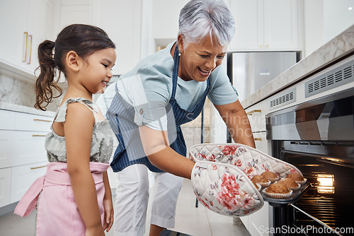 Image of Muffins, learning and grandmother with girl cooking and taking out cupcakes from oven. Education, kitchen and happy grandma teaching child how to bake, bonding and enjoying quality time together.