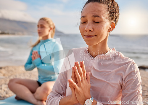 Image of Yoga, meditation and woman friends on a beach together for mental health or wellness to meditate in summer. Exercise, diversity or nature with a female yogi and friend meditating outside for fitness