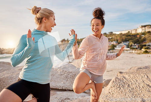 Image of Women friends, yoga and ocean in morning with stretching pose for health, zen wellness or high five for support. Black woman, exercise group and comic laugh for balance, peace and solidarity at beach