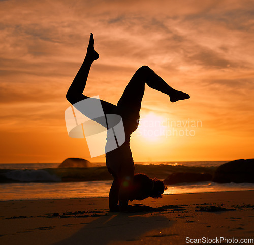 Image of Yoga, silhouette or handstand on sunset beach, ocean or sea in evening workout or relax exercise training. Yogi, woman or sand balance pose at sunrise for healthcare wellness fitness or strong body