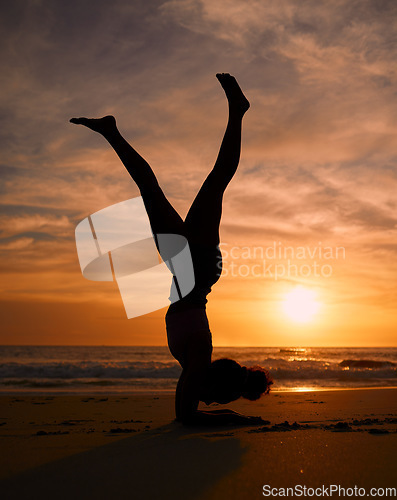 Image of Yoga woman, silhouette or handstand on sunset beach, ocean or sea in workout or relax exercise training. Yogi, pilates or sand balance pose at sunrise for healthcare wellness fitness or strong body