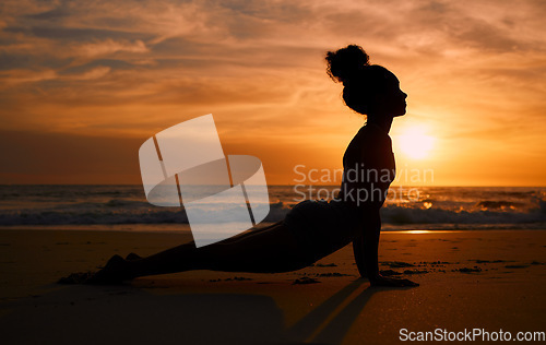 Image of Sunset yoga, stretching and silhouette of a woman at the beach for mindfulness training at night. Meditation, zen and girl beginning a pilates pose at the sea in the evening for spiritual exercise