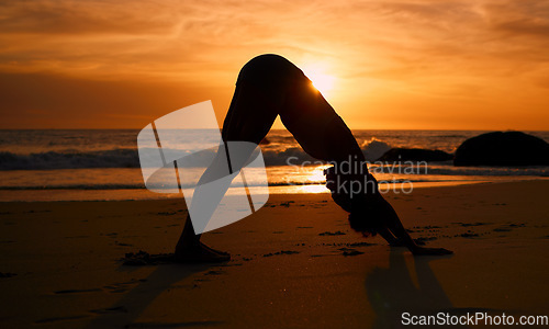 Image of Yoga, silhouette and downward dog on sunset beach, ocean or sea in workout or relax exercise training. Yogi, woman and sand stretching at sunrise healthcare wellness, fitness pilates or strong body