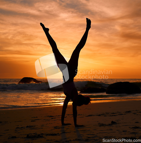 Image of Yoga woman, silhouette or handstand on sunset beach, sea or ocean in workout or relax exercise training. Yogi, pilates or sand balance pose at sunrise for healthcare wellness fitness or strong body