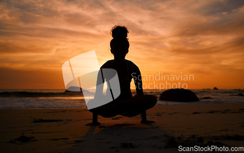 Image of Sunset, yoga and silhouette of a woman on the beach in a lotus pose doing a meditation exercise by the sea. Peace, zen and shadow of a calm female doing a pilates workout outdoor at dusk by the ocean