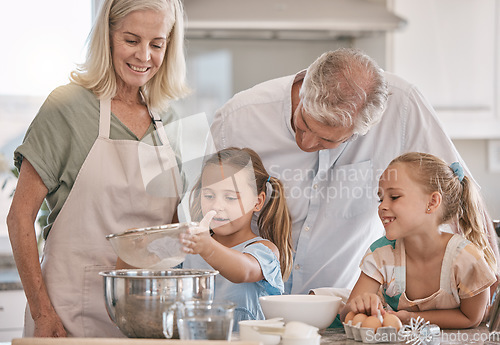 Image of Family, baking and children helping grandparents in their home kitchen. Senior woman, man and girl kids learning about food, cooking or dessert recipe with love, care and quality time for development