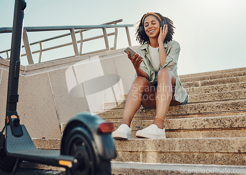 Image of Black woman outdoor, smartphone and headphones with scooter, music and travel with 5g network for audio streaming in city. Sustainable transportation, listen to audio or podcast and relax on steps