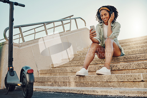 Image of Black woman outdoor, scooter and phone with headphones for music, eco friendly travel and 5g for audio streaming in city. Sustainability, listen to podcast and relax on steps with transportation