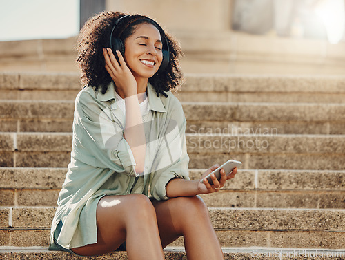 Image of Black woman outdoor, mobile phone and headphone for music, travel and 5g network for audio streaming in city. Happy in Miami with peace, listen to podcast and relax on steps with internet connection