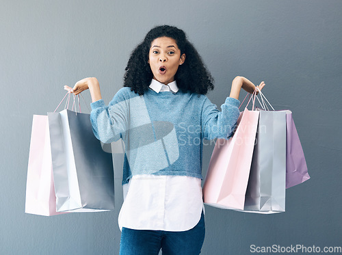 Image of Wow, sale and portrait of woman with shopping bags, retail therapy and surprise at gift on a wall. Deal, excited and happy girl holding products from a shop, market or mall on a grey background