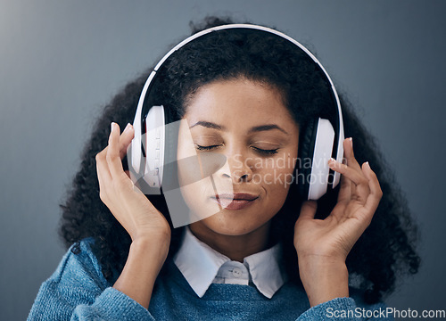 Image of Headphones, music and face of black woman relax with wall background listening to audio, radio and song. Freedom, calm and happy girl in studio for peace, mindset and streaming wellness podcast