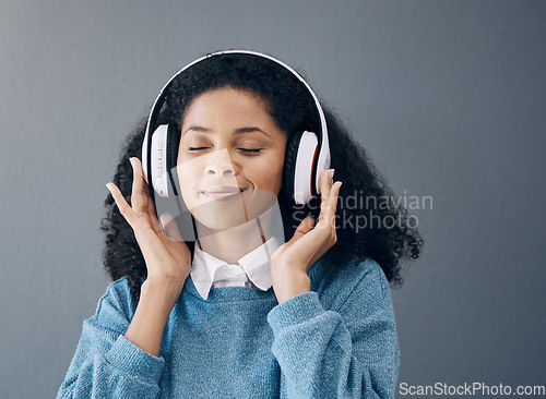 Image of Relax, music and black woman in studio with peace, streaming or good mood on grey background. Radio, podcast and girl with positive, mindset or audio, online or playlist on advertising isolated space