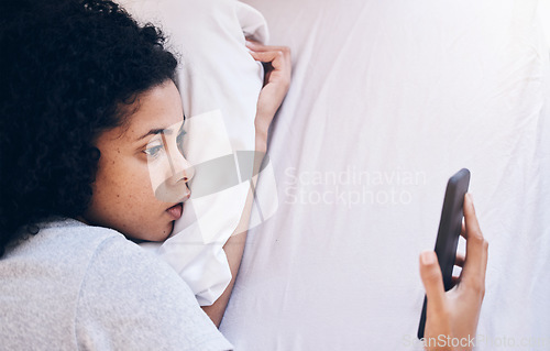 Image of Phone, depression and woman lying in her bed while watching videos on social media or the internet. Tired, sleepy and depressed female with insomnia networking on a cellphone in her bedroom at home.