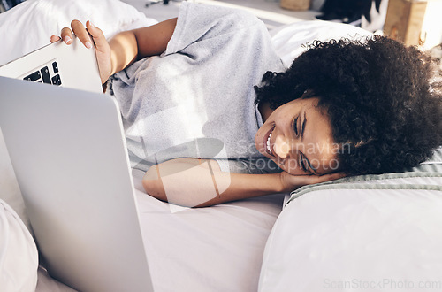 Image of Laptop, movie and woman watching in bed on the internet while relaxing or resting at her home. Happy, laugh and female streaming an online funny comedy film on a computer while lying in her bedroom.