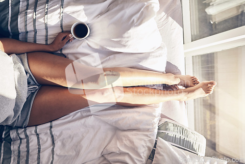 Image of Relax, bed and above of a woman with coffee, stress relief and resting by a window in the morning. Peace, legs and lazy girl in the bedroom with a drink and comfortable in the sunshine for a break