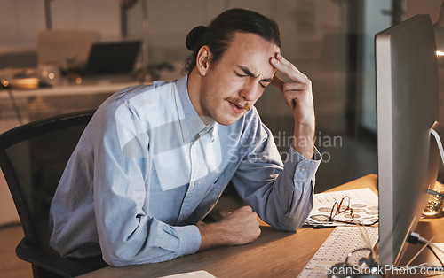 Image of Man, headache and burnout by computer at night in stress for overworked, anxiety or depression at the office desk. Male employee suffering bad head pain, ache or mental health issues at the workplace