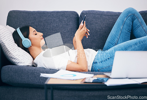 Image of Headphones, sofa and woman student on study break for mental health, relax podcast and music streaming services. Smartphone, listening to audio and young person on couch with calm mindset or wellness