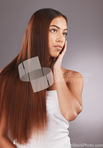 Image of Woman, long hair and face for skincare, beauty or cosmetics against a gray studio background. Attractive female touching skin in satisfaction for self love or facial, haircare and cosmetic treatment