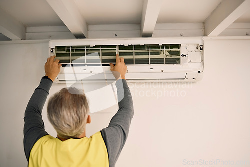 Image of Construction, installation and back of a man with an air conditioner, maintenance and ac repair. Building, service and a handyman fitting a tool on a wall of a home for home improvement and heat