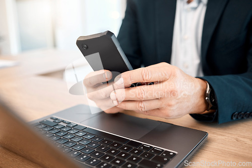 Image of Hands, phone and research with a business man typing a text message while working on his laptop. Mobile, communication and networking with a male manager or employee reading an email at work