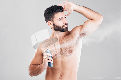 Image of Spray, deodorant and man with cosmetics, morning routine or grooming on grey studio background. Male, perfume or fragrance for fresh scent, self care or hygiene with guy or antiperspirant on backdrop