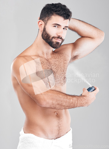 Image of Portrait, deodorant and man spray armpit for hygiene, fresh scent and grooming isolated on a gray studio background. Cosmetics, wellness and young male model with perfume, fragrance or antiperspirant